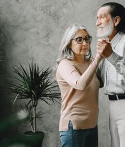 Um casal de idosos dançam de mãos dadas