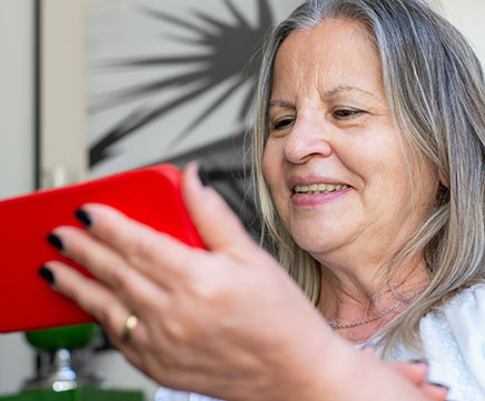 Uma senhora idosa está assistindo coisas pelo celular