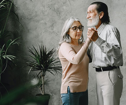 Um casal de idosos dançam de mãos dadas