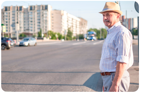 Homem atravessando a rua. Ele usa chapéu e camisa clara.