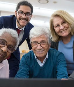 Três homens e uma mulher, estão olhando diretamente para uma tela de computador.