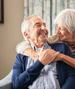 Um casal de idosos se abraçam e se olham diretamente nos olhos